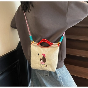Detail of dachshund embroidery and colorful braided strap on cream nylon crossbody bag