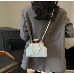 Détail du sac coquille bleu clair avec applique papillon 3D et accents de perles