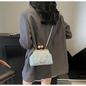 Détail d'un sac papillon en dentelle bleu clair avec bandoulière en perles sur un modèle