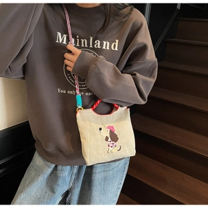 Detail of cream canvas bag with colorful woven rope strap and cute dog embroidery