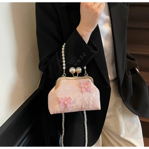 Détail d'un sac brodé rose avec papillons en tulle et finitions élégantes en perles