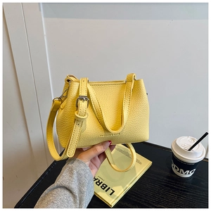 Détail d'un sac seau jaune en cuir litchi avec poignée solide et bandoulière réglable