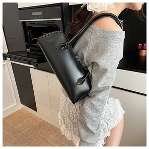 Chic black matte leather baguette bag worn by a model in a modern minimalist setting