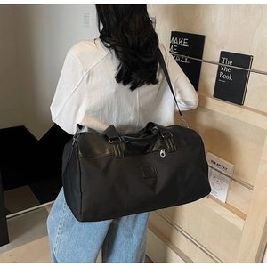 Detail of black large capacity travel bag in canvas and leather worn as a crossbody
