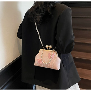 Sac coquille rose avec broderie papillon et bandoulière en perles sur un modèle