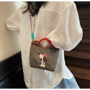 Detail of dachshund embroidery on brown canvas crossbody bag with braided rope handles