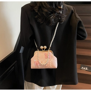 Détail du sac brodé rose avec papillon 3D, bandoulière en perles et fermoir rétro chic
