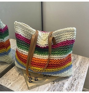 Detailed view of colorful woven straw tote bag with multi-color stripes and leather handles