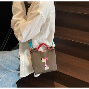 Detail of coffee canvas tote with cute dog embroidery and braided colorful rope handles