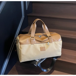 Detail of a large two-tone canvas travel bag with brown leather handles on wooden steps
