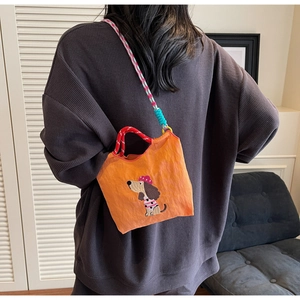Detail view of bright orange dachshund embroidery crossbody bag with woven straps