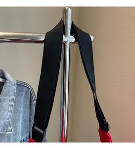 Detail of adjustable black wide strap on red canvas bag showing woven texture and buckle