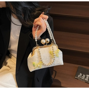 Détail du sac coquillage en dentelle blanche avec papillons jaunes et fermoir perle