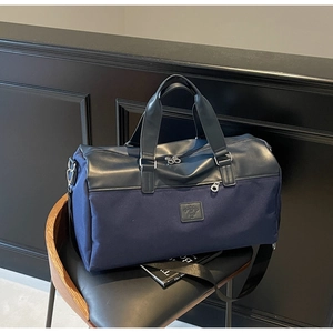 Detail of navy blue travel bag on a leather chair showing canvas texture and adjustable strap
