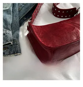 Detail view of the silver studs on a dark red leather pleated crossbody shoulder bag