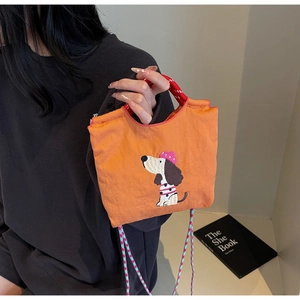 Detail of orange dachshund bag with embroidered dog pattern and colorful rope strap