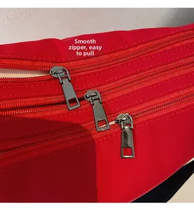Detail view of the smooth silver zippers and triple-layer storage on red canvas bag