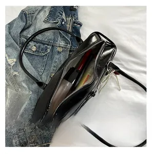 Detail view of black glossy pillow bag interior capacity with pearl pendant accessory