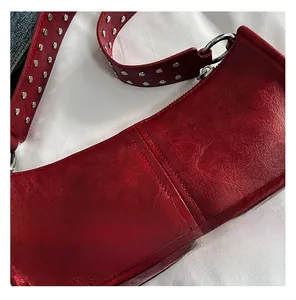 Macro shot of red faux-oil wax leather handbag with silver stud details on shoulder strap