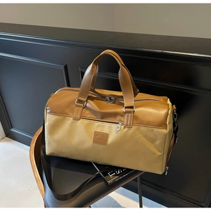 Detail of a large khaki canvas travel bag with brown leather handles on a chair