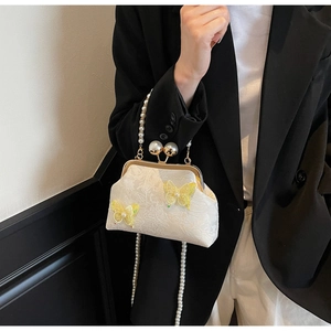 Détail du sac coquille en dentelle blanche avec papillons jaunes et chaîne de perles