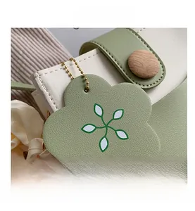 Detail of color-block leather bag with flower charm and wooden button on the strap