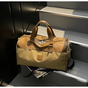 Detail view of khaki canvas travel bag with brown leather handles and a long shoulder strap