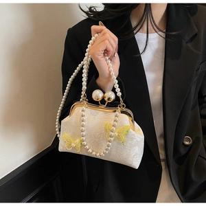 Détail du sac coquille blanc brodé avec applique papillon 3D et anse en perles