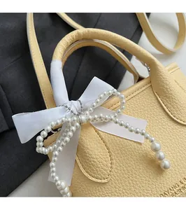 Close-up of a yellow pebbled leather bucket bag featuring a pearl bow and ribbon detail