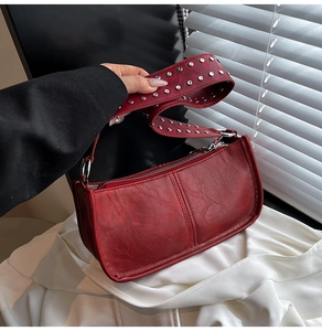 Detail of dark red vintage underarm bag featuring metallic silver studs on wide strap