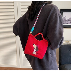 Detail of red sausage dog embroidery on crossbody bag with textured braided strap