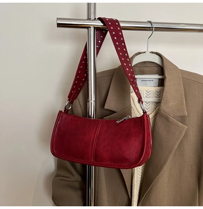 Detail of silver rivets on the dark red faux leather shoulder bag with a metal zipper