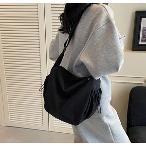 Detail of black large capacity canvas crossbody bag with side drawstring and natural pleats