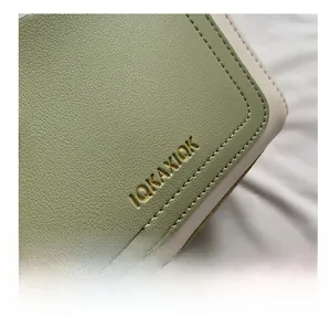 Detailed close-up of the IQKAXIQK logo on a textured lychee grain leather crossbody bag