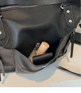 Detailed view of black pebbled leather tote with silver studs and side magnetic pocket