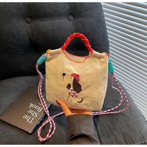 Close-up of beige canvas dachshund embroidery bag with colorful braided strap and drawstring
