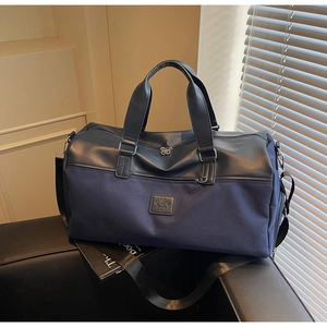 Detail of navy blue canvas travel bag featuring leather stitching and adjustable strap