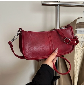 Detail of vintage red leather crossbody bag featuring matte texture and silver hardware
