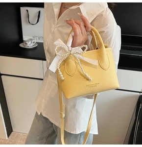 Detail of yellow pebble texture mini bucket bag with pearl bow and silk ribbon decoration