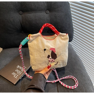 Detail of dachshund embroidery on beige canvas bag with colorful braided shoulder strap