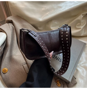 Detail showing the wide shoulder strap with silver metal rivets on dark brown bag