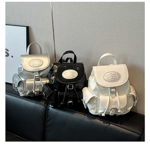 Close-up of stylish mini backpacks in silver, black and white with metal buckle details