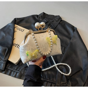 Détail du sac en dentelle beige avec appliques papillons jaunes et bandoulière en perles