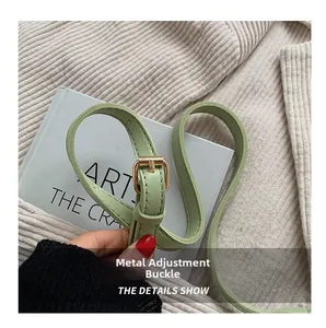 Detail shot of the golden metal adjustment buckle on a light green faux leather bag strap