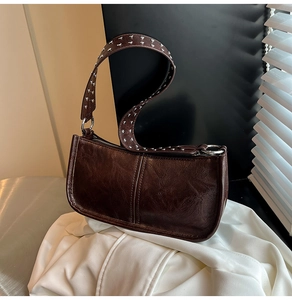 Detail of vintage dark brown leather shoulder bag with silver rivet-studded strap