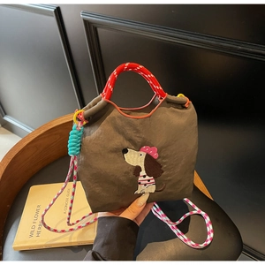 Detail of dark grey nylon crossbody bag featuring cute dog embroidery and woven handles