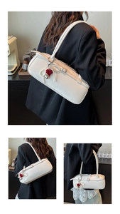 Detail of white leather underarm bag featuring pearl chain and red heart charm accent