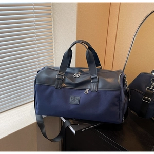 Detail view of large navy canvas travel bag with black leather handles and shoulder strap