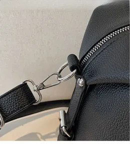 Detailed macro view of silver metal buckles and black litchi pattern leather on the bag