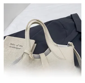 Detail showing high-quality lychee grain leather texture and handle on a cream bucket bag